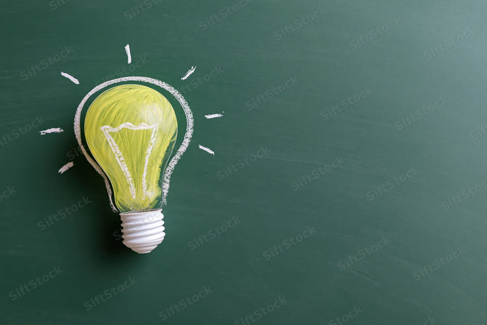 Chalk-drawn lightbulb glowing on green blackboard surface