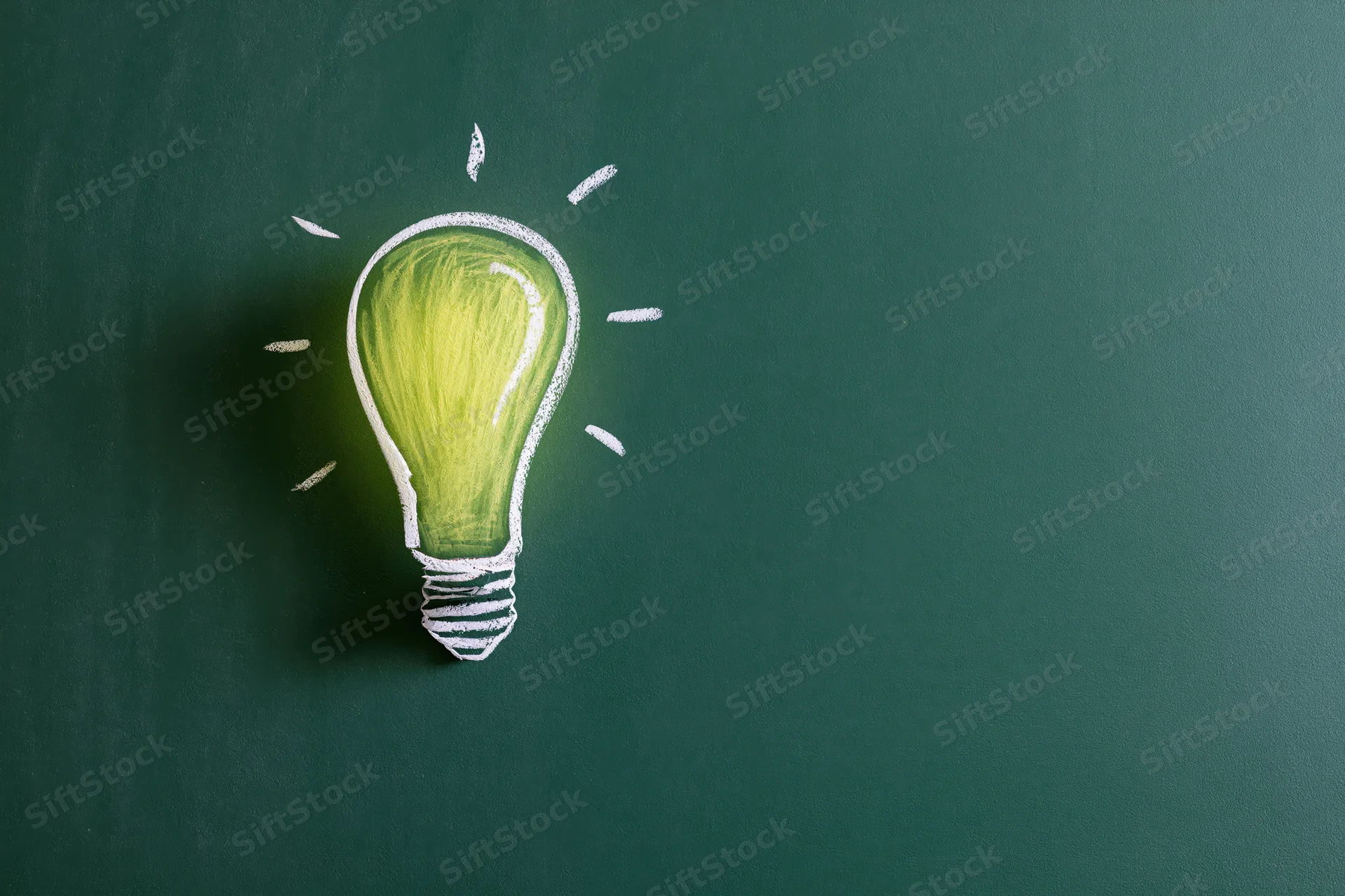 Chalk drawing of a glowing light bulb on a green blackboard