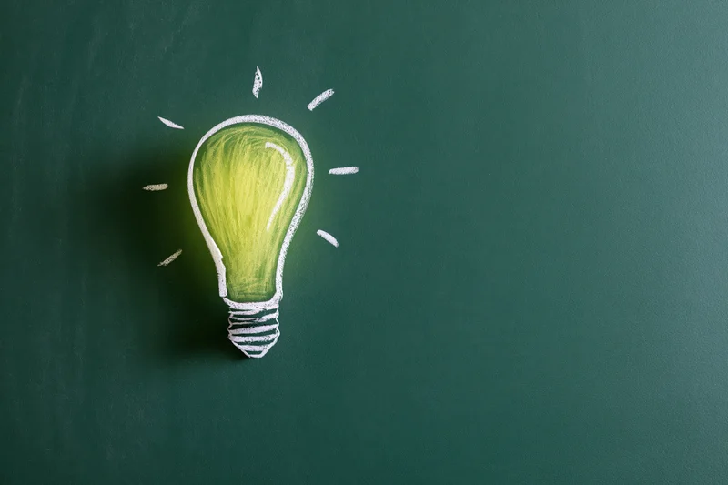 Chalk drawing of a glowing light bulb on a green blackboard