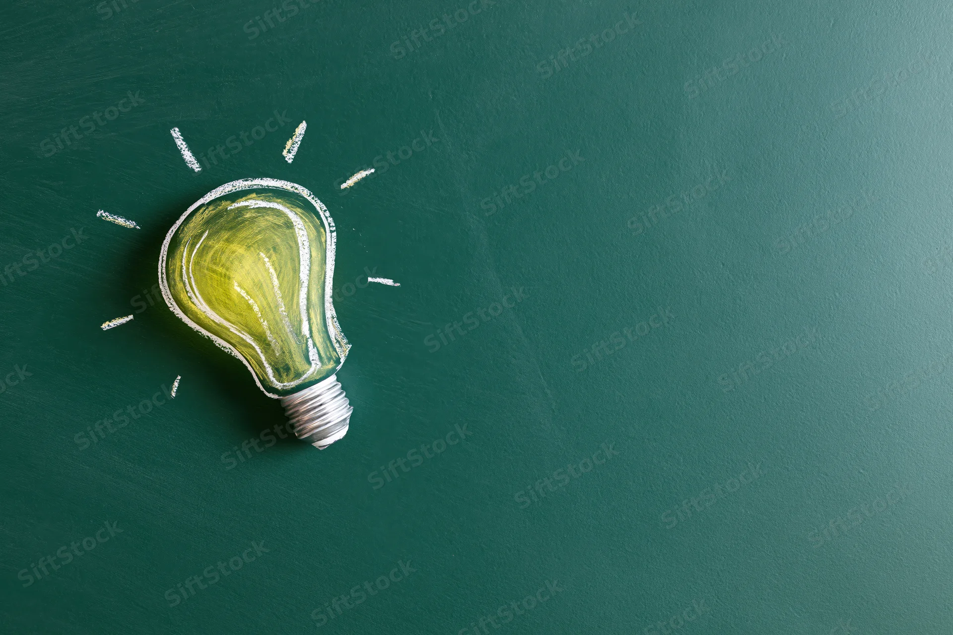 Chalk drawing of a glowing light bulb on a green blackboard