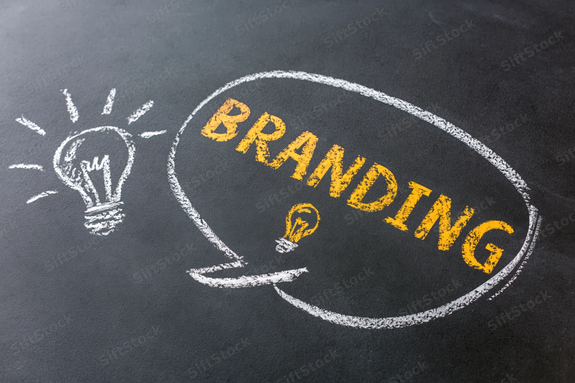 Chalk drawing of a speech bubble with the word branding and a lightbulb on a blackboard