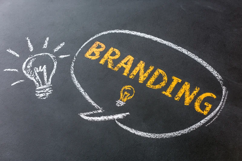 Chalk drawing of a speech bubble with the word branding and a lightbulb on a blackboard