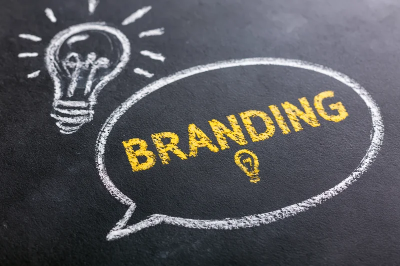 Chalk drawing of a speech bubble with the word branding and a lightbulb on a blackboard