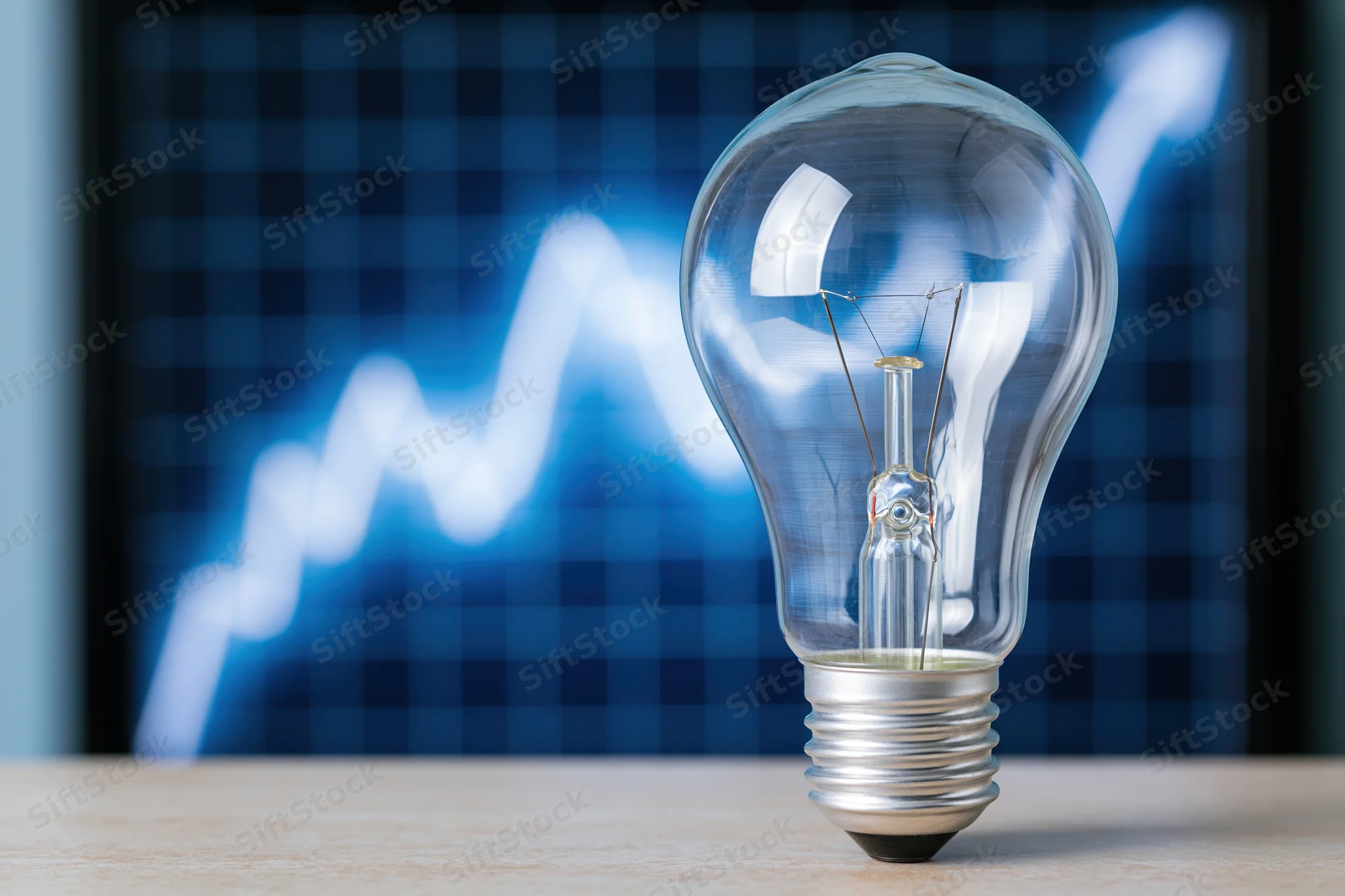 Unlit glass lightbulb on wooden surface with blue digital graph in background