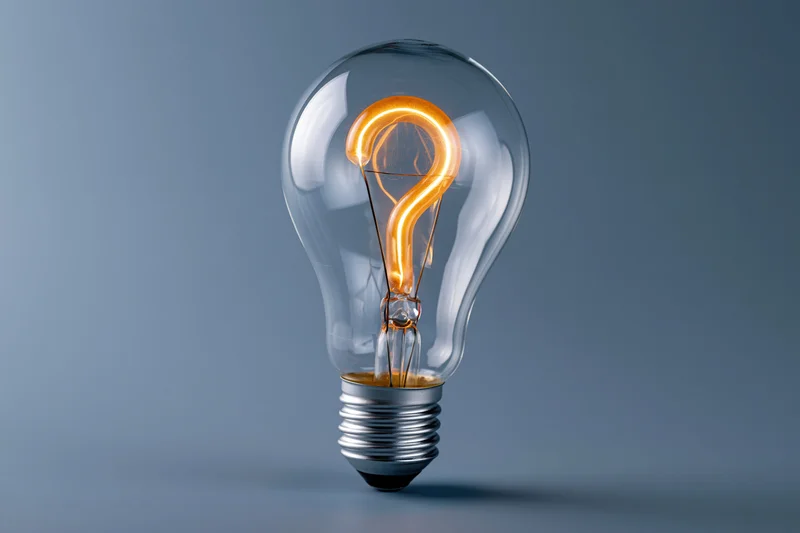 Glowing incandescent lightbulb with question mark filament on a gray background