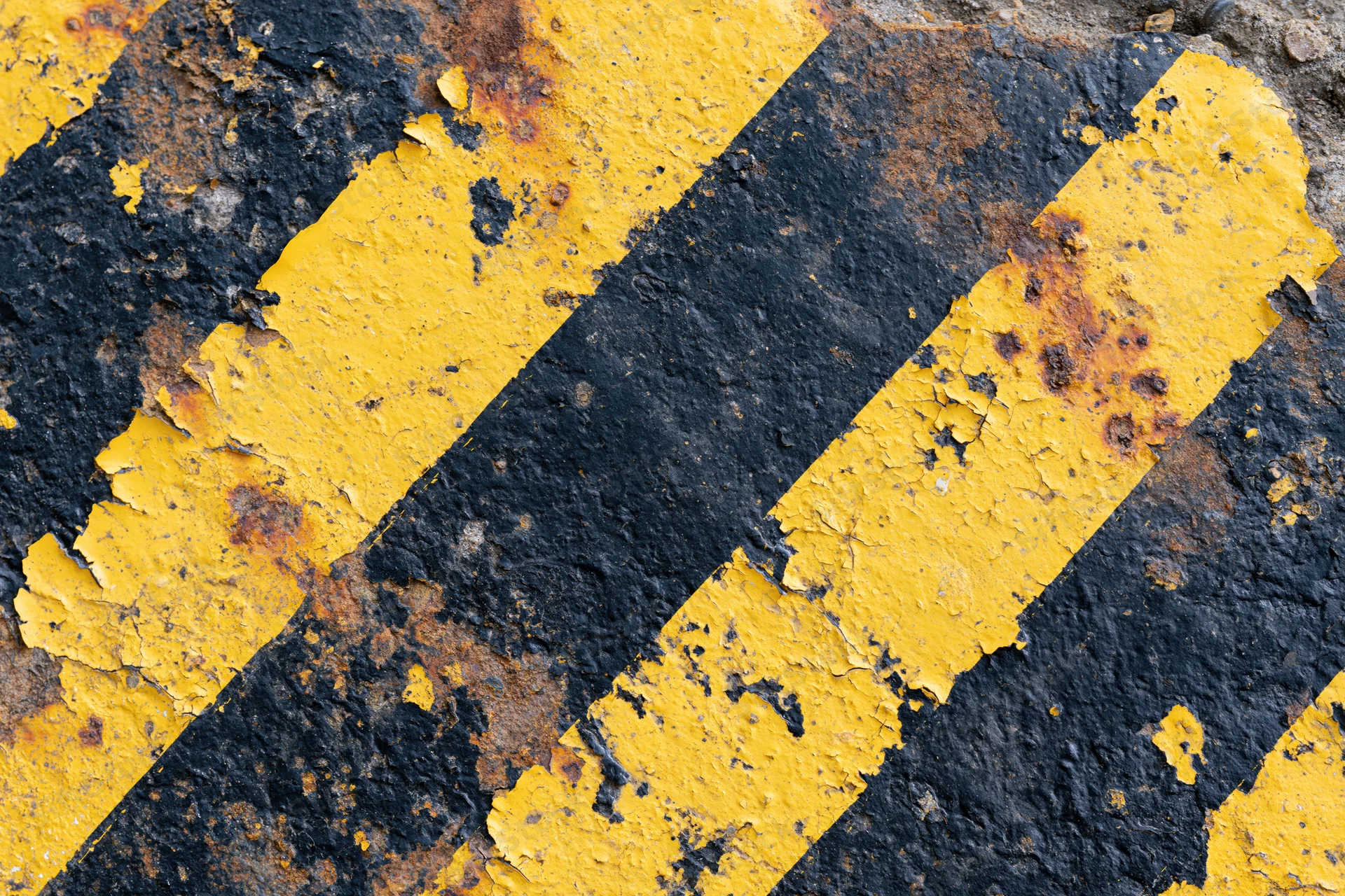 Weathered yellow and black hazard stripes on a cracked concrete surface