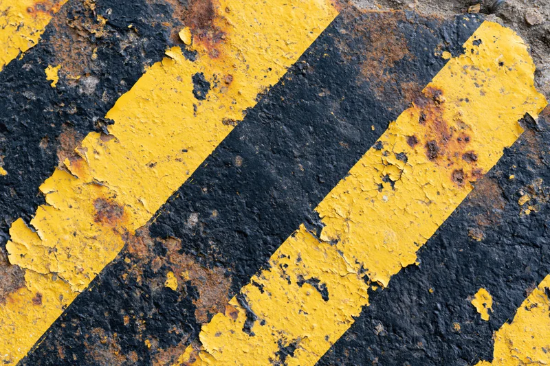 Weathered yellow and black hazard stripes on a cracked concrete surface