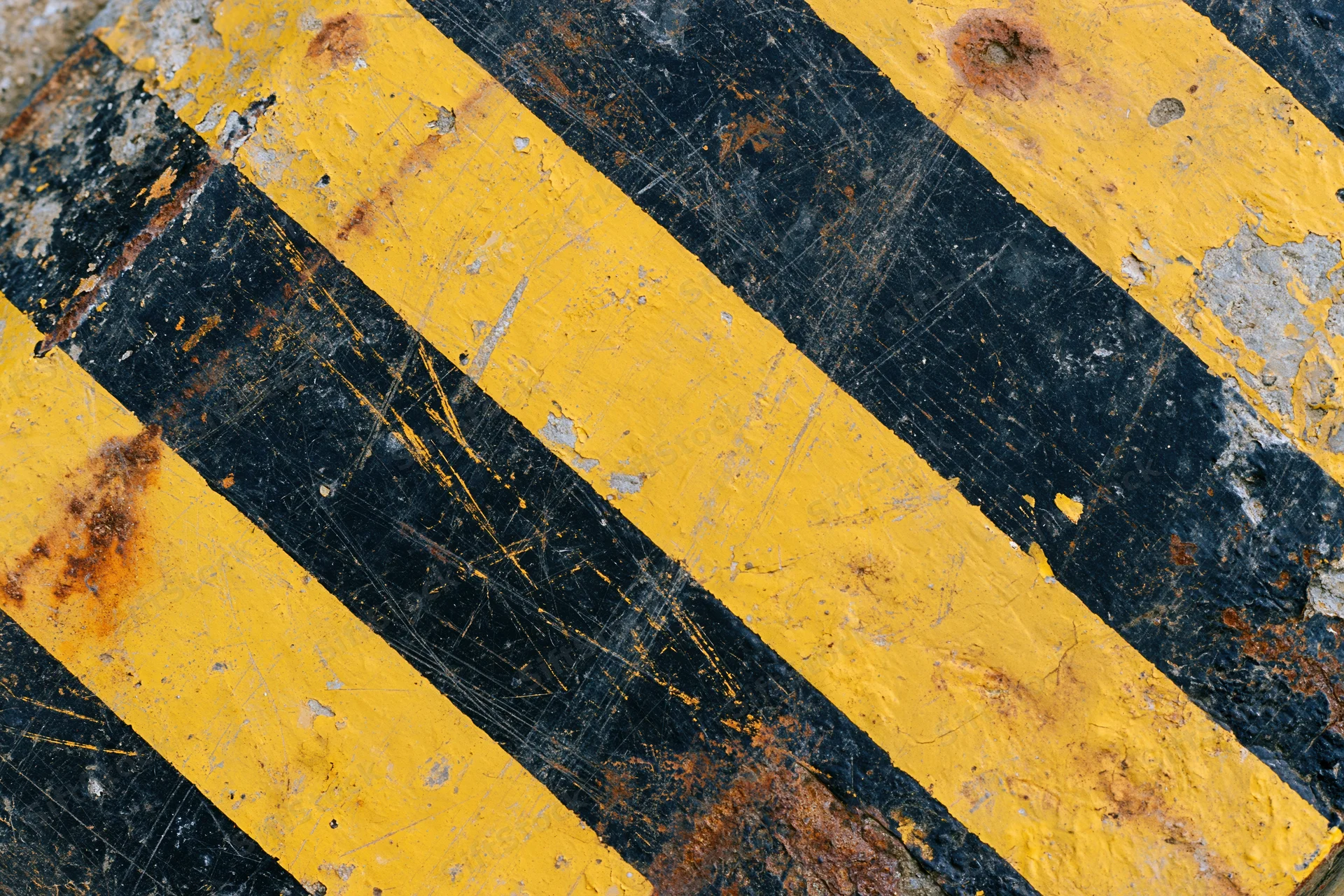 Weathered yellow and black hazard stripes on a corroded metal surface