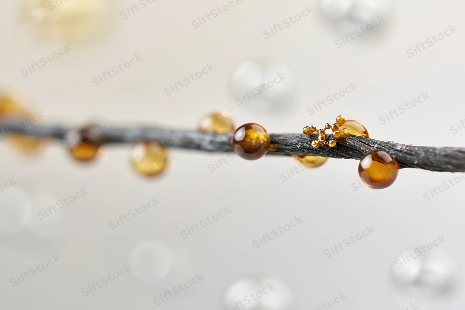 Closeup of a dark human hair strand with oil droplets and sebum beads on a light background