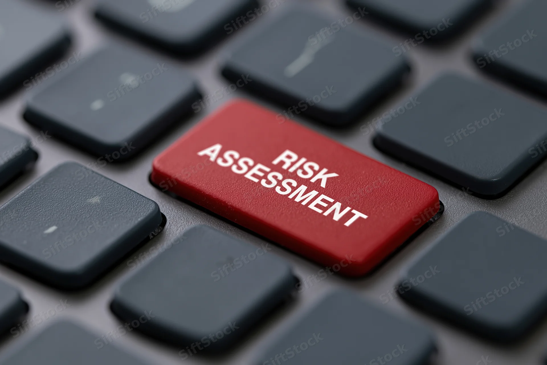 Red button labeled risk assessment on dark grey laptop keyboard