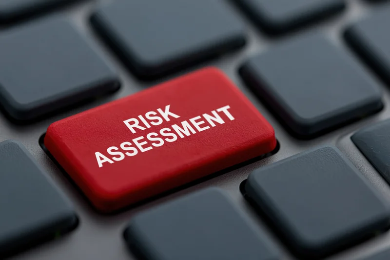 Red button labeled risk assessment on dark grey laptop keyboard