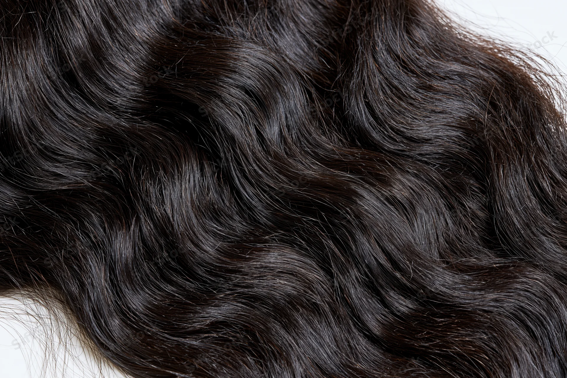 Close-up of dark black wavy human hair extensions on white background