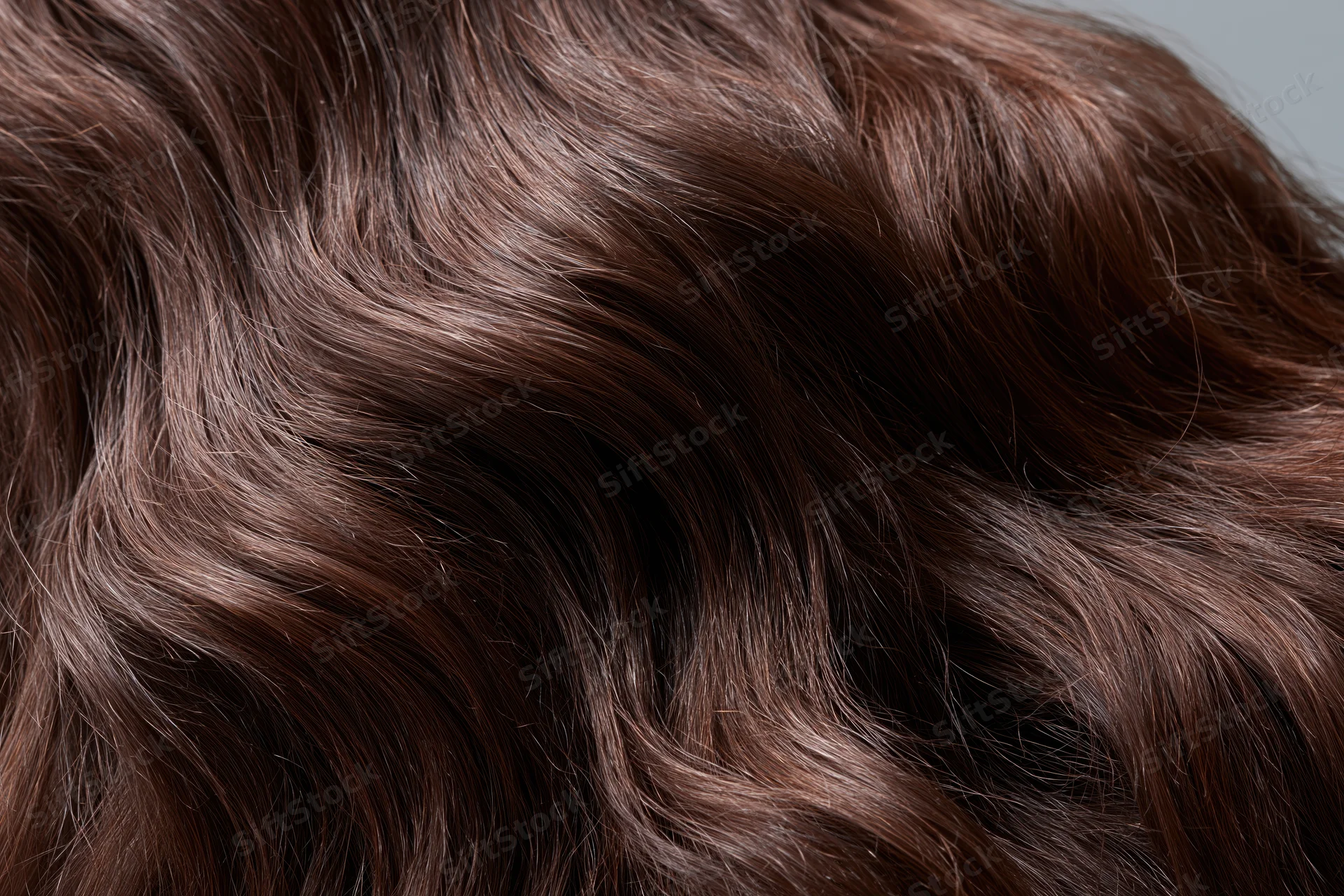 Closeup of dark brown wavy hair with glossy texture filling the frame