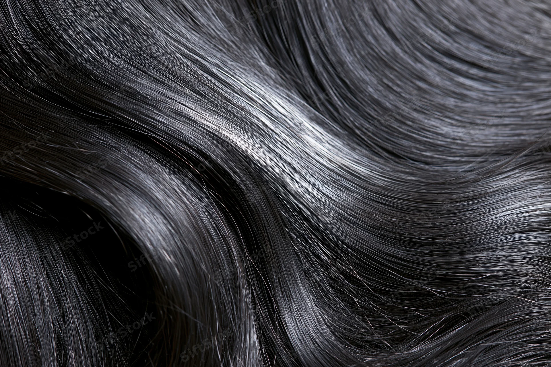 Close-up of glossy dark black hair strands flowing in soft waves