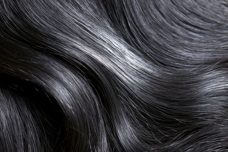 Close-up of glossy dark black hair strands flowing in soft waves