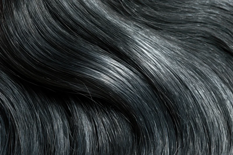 Close-up of glossy dark black hair strands flowing in soft waves