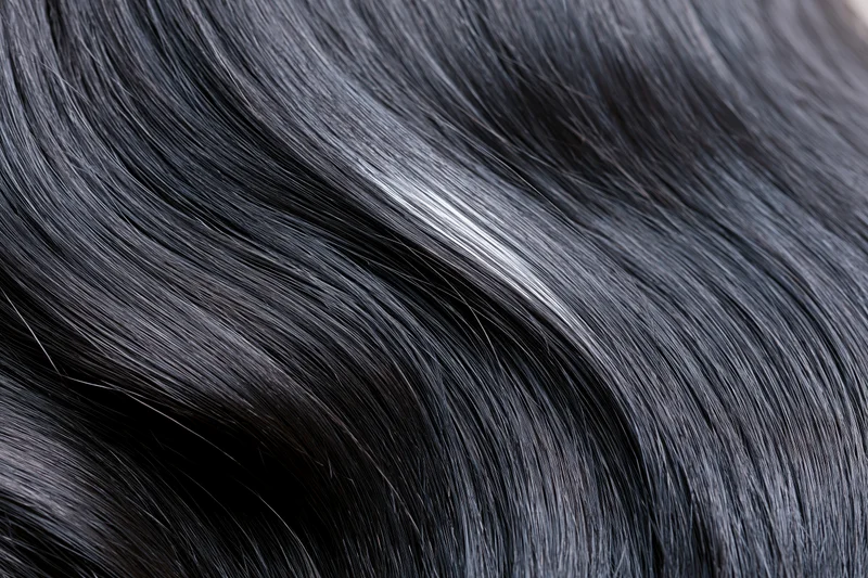 Close-up of glossy dark black hair strands with natural sheen