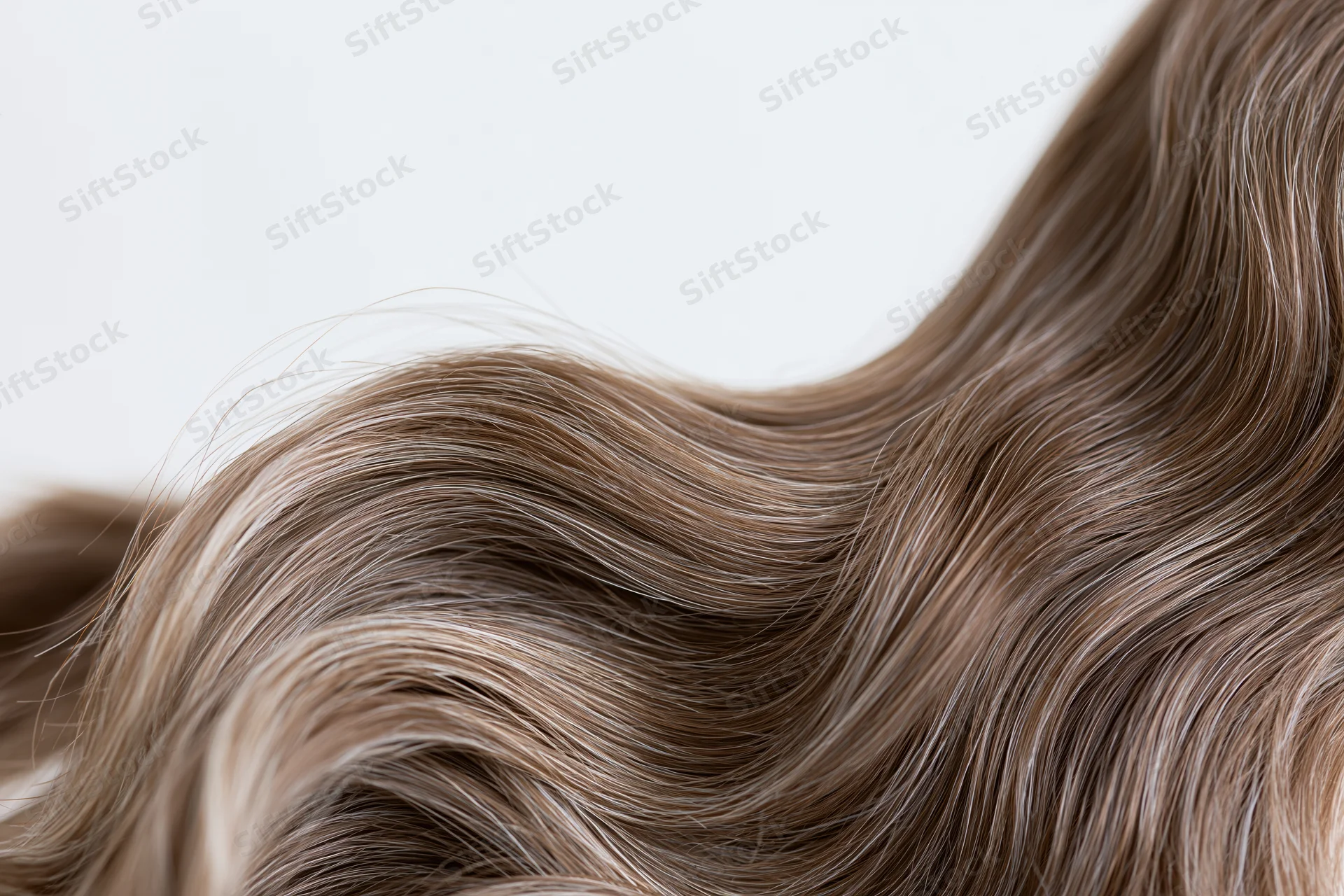 Closeup of loose wavy brown hair strands flowing against white background