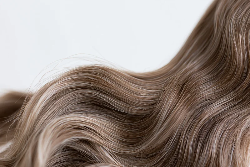 Closeup of loose wavy brown hair strands flowing against white background