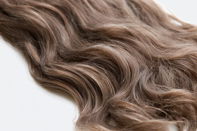 Close-up of loose wavy brown hair strands on white background