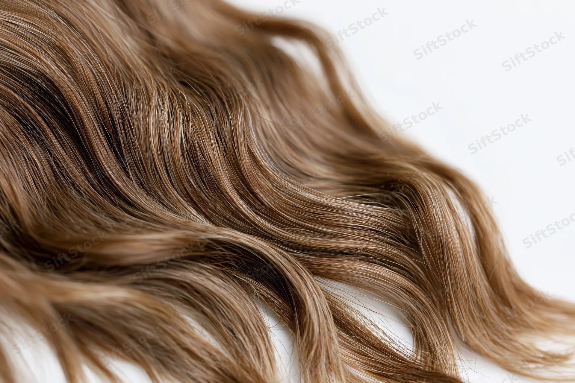 Close-up of loose wavy brown hair strands on white background