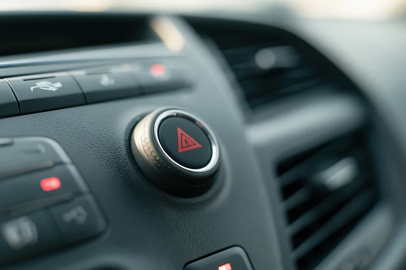 Close-up of car dashboard center console showing hazard warning button and controls