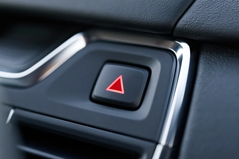 Close-up of a red triangle hazard warning button on a car dashboard interior