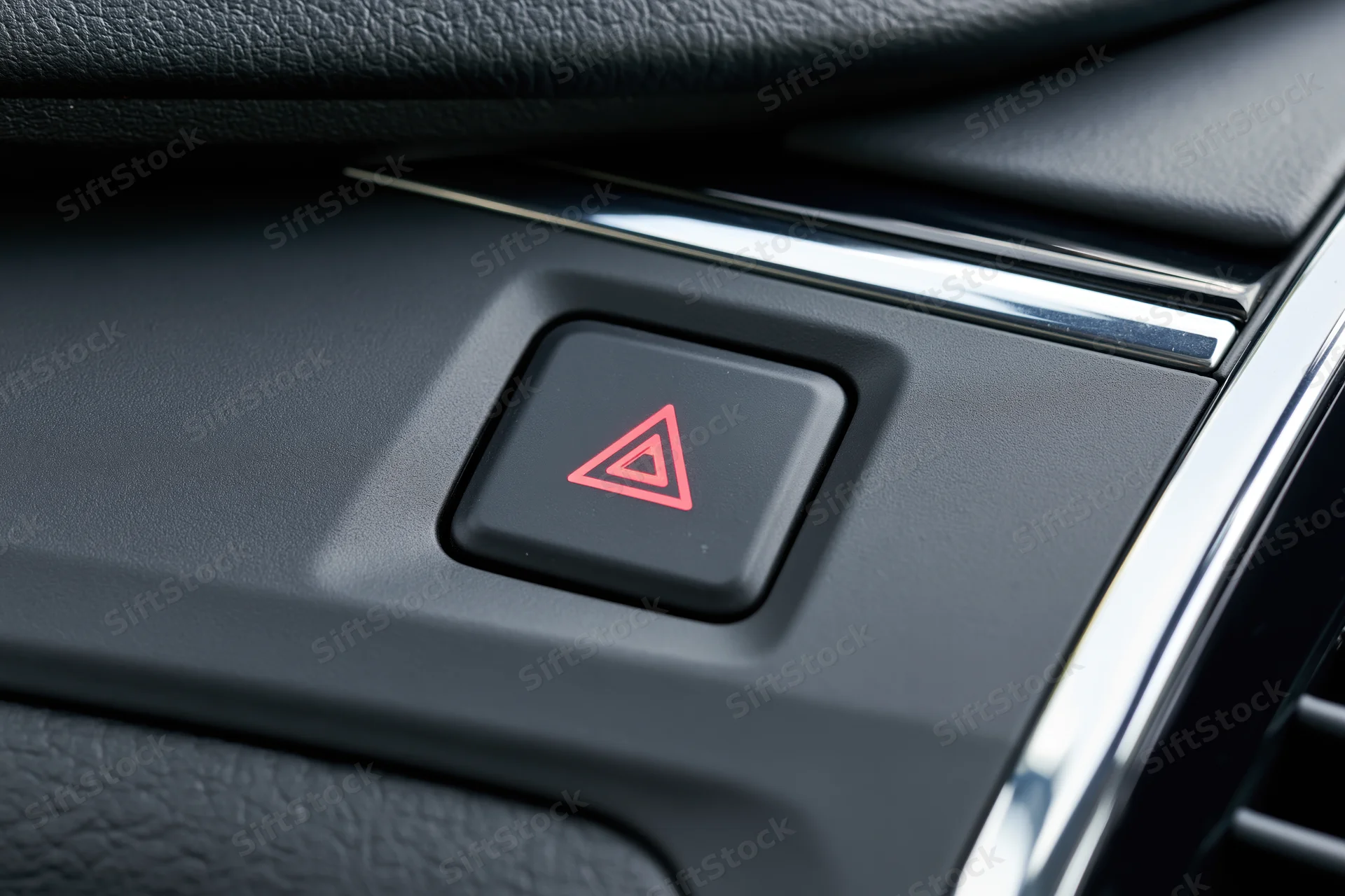 Close-up of a red triangle hazard warning button on a car dashboard interior