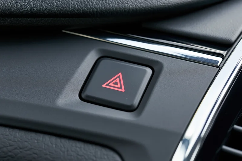 Close-up of a red triangle hazard warning button on a car dashboard interior