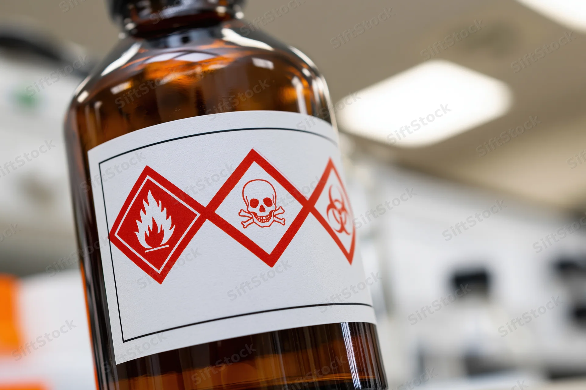 Close-up of a dark amber chemical bottle with ghs hazard label in a laboratory setting