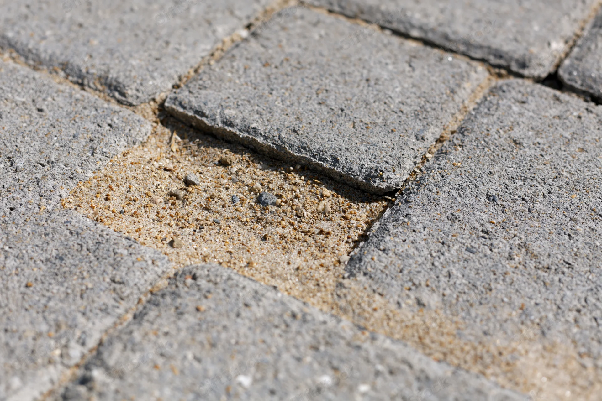 Damaged concrete brick pavement with missing tile and exposed sand joint