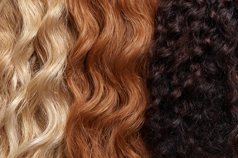 Three hair texture samples arranged side by side showing blonde wavy, brown wavy, and black curly hair