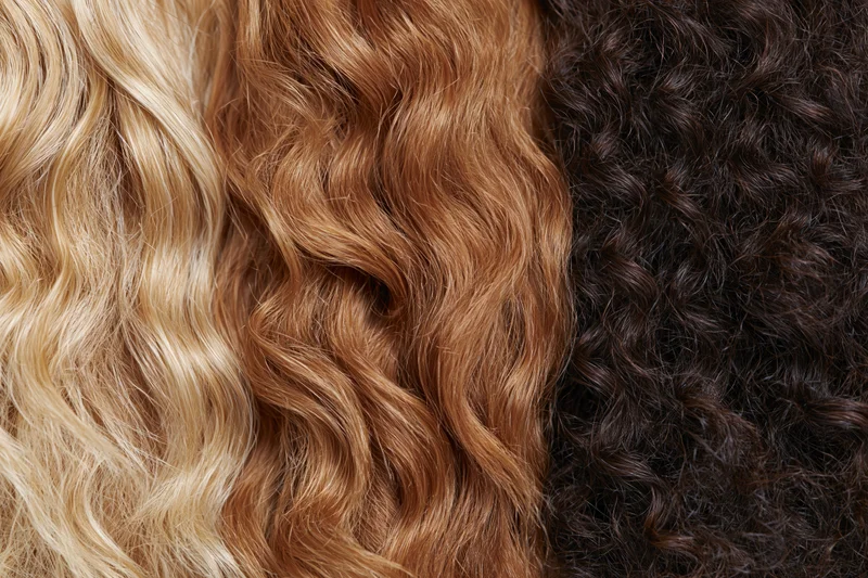 Three hair texture samples arranged side by side showing blonde wavy, brown wavy, and black curly hair