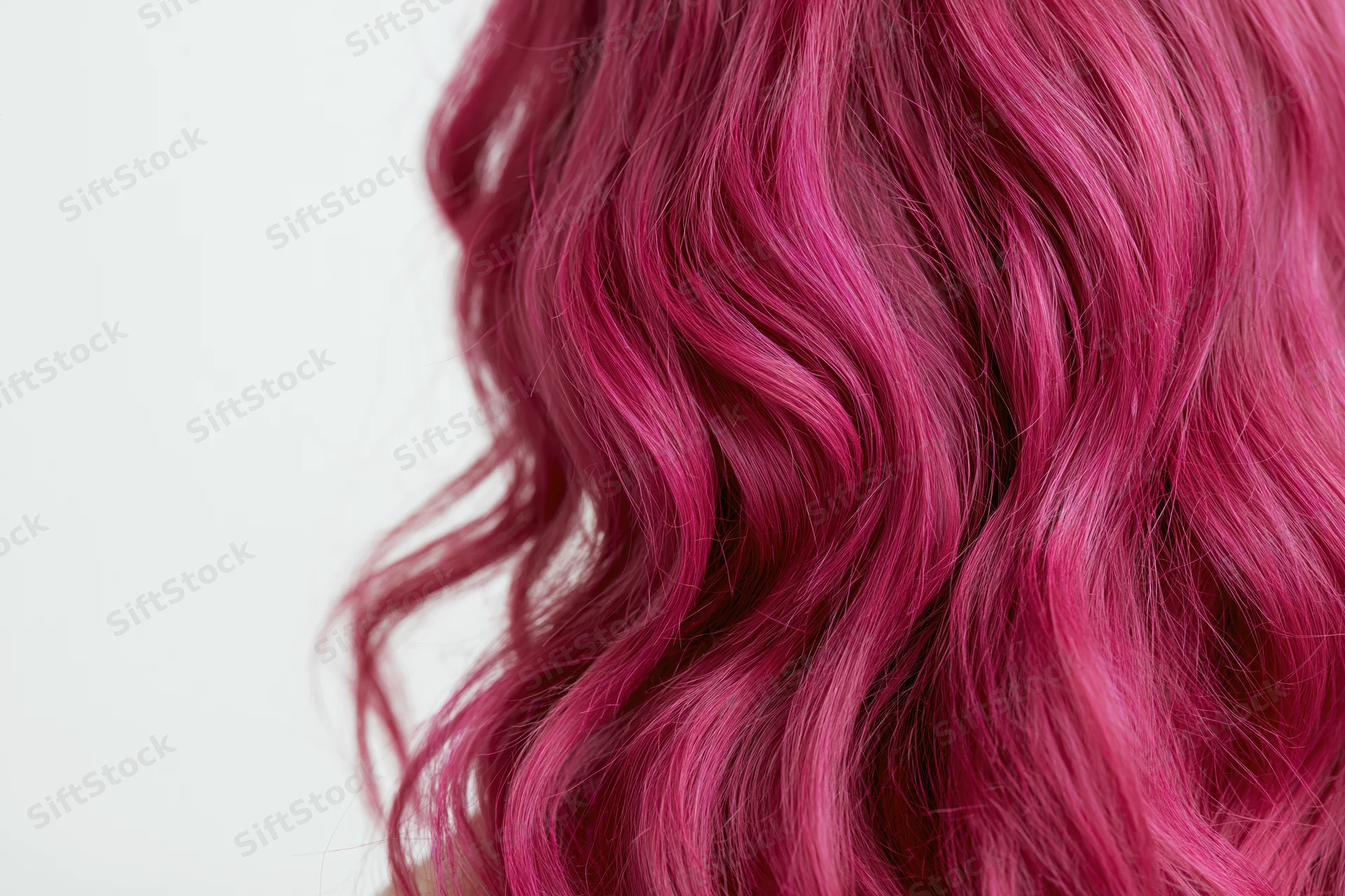 Close-up of wavy dyed magenta-pink hair with volume against white background