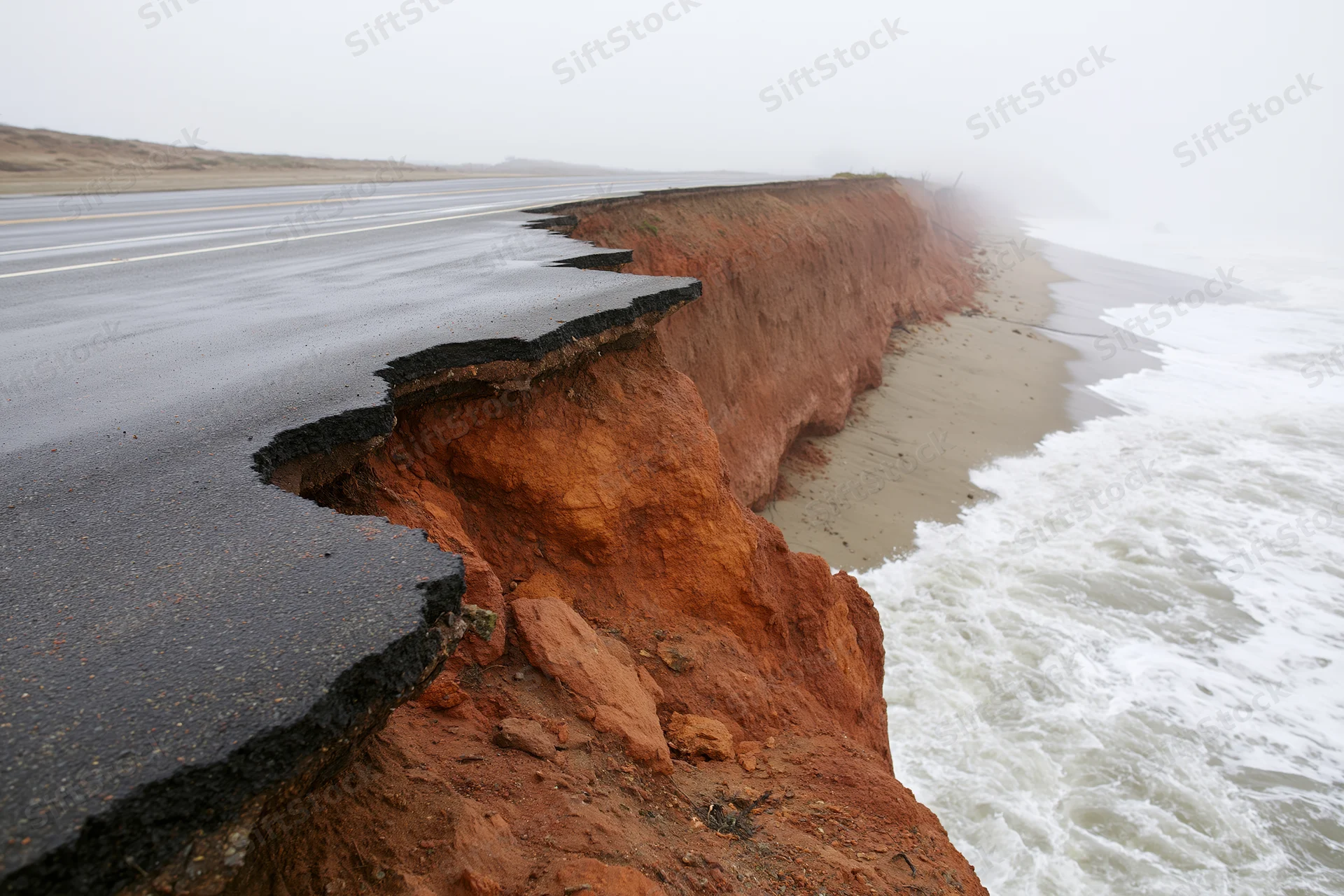 Damaged coastal road with eroded asphalt edge near ocean waves
