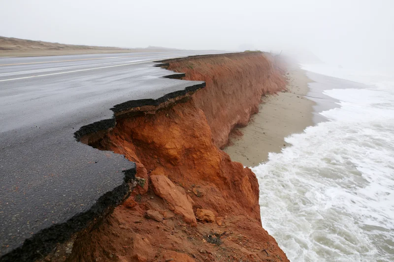 Damaged coastal road with eroded asphalt edge near ocean waves