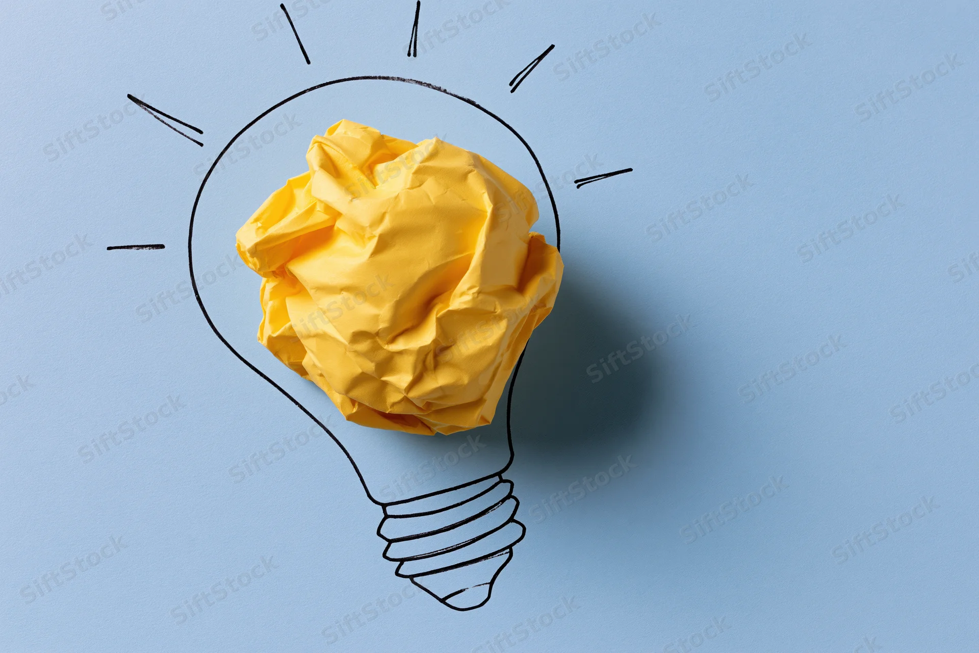 Crumpled yellow paper ball inside hand-drawn lightbulb outline on blue background