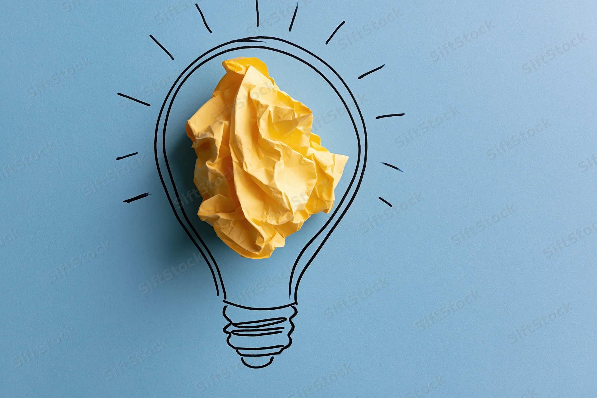Crumpled yellow paper ball inside hand-drawn lightbulb on blue background