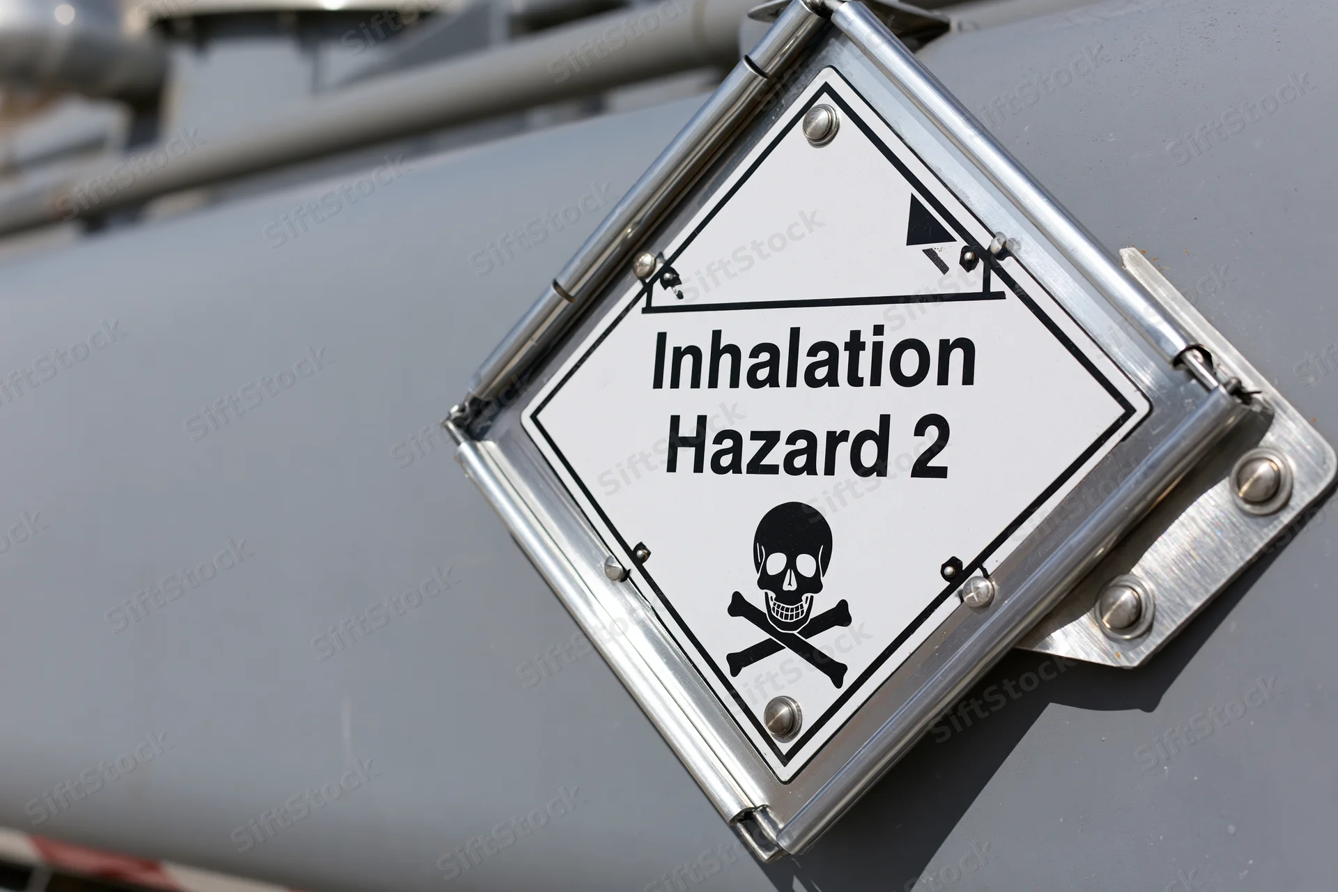 Diamond-shaped hazmat placard reading inhalation hazard 2 with skull and crossbones symbol mounted on metal surface