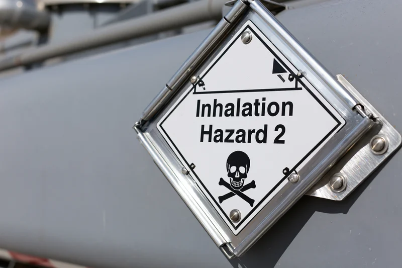 Diamond-shaped hazmat placard reading inhalation hazard 2 with skull and crossbones symbol mounted on metal surface