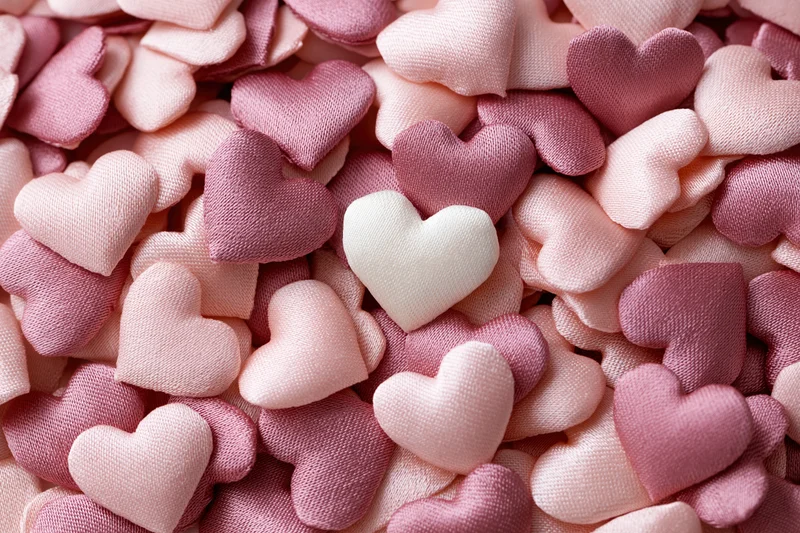 Pile of small fabric hearts in pink and white tones filling the frame