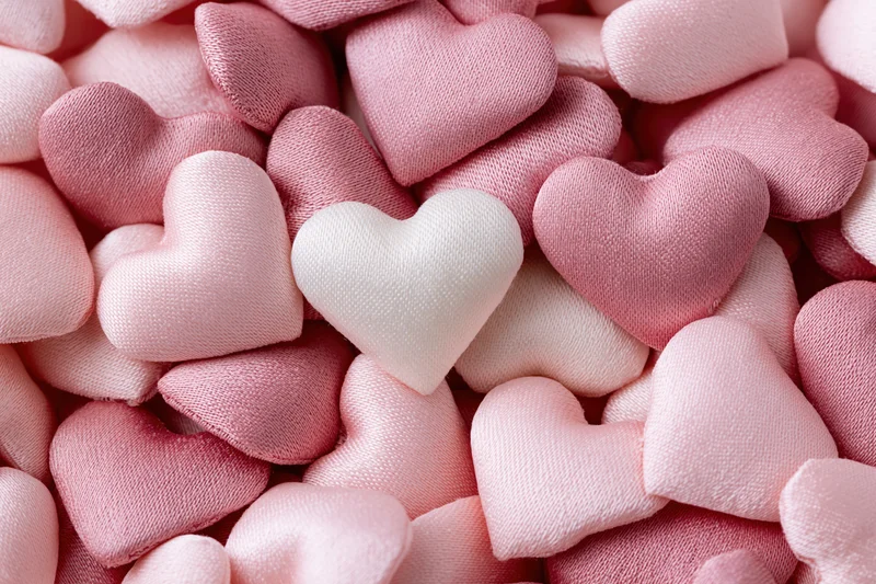 Pile of small fabric hearts in pink and white, closeup view