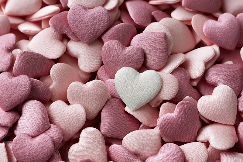 Pile of small fabric hearts in pink and white tones filling the frame