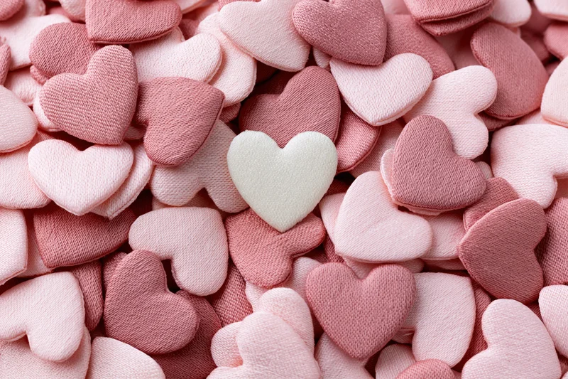 Pile of small fabric hearts in pink and white tones filling the frame