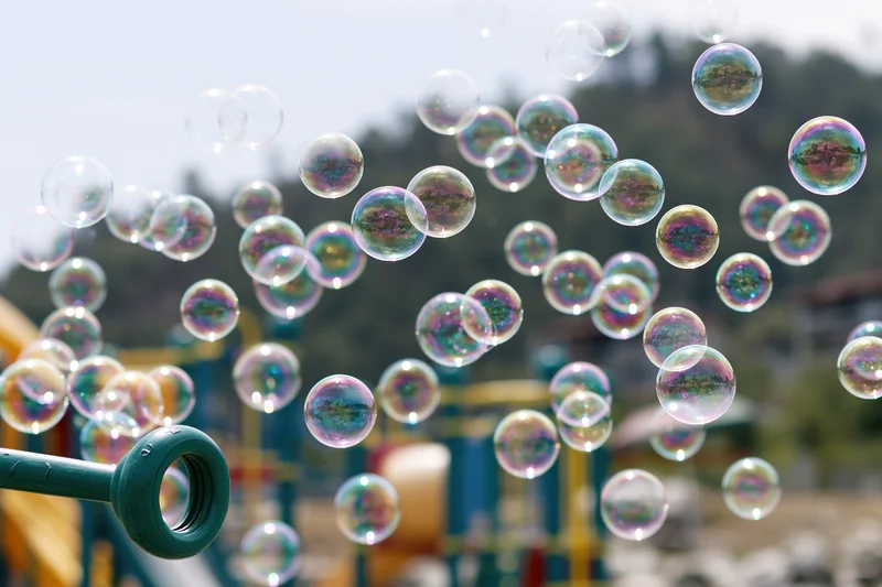 Soap bubbles floating in midair above a children's playground on a sunny day