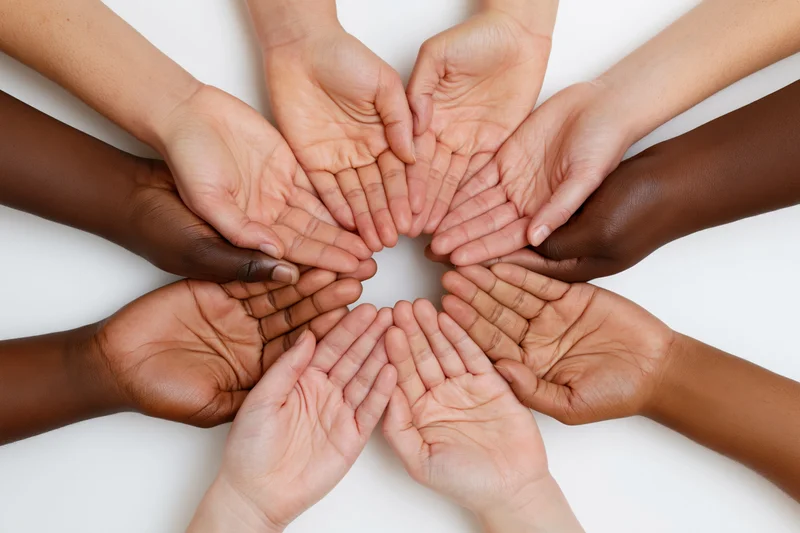 Diverse hands joined in a circle on white background