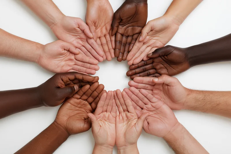 Diverse hands joined in a circle on white background