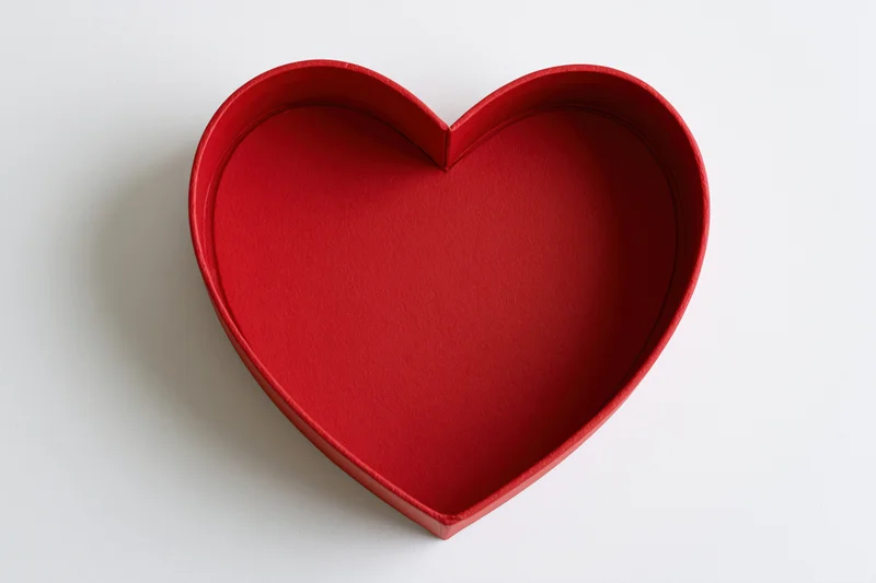 Red heart-shaped gift box lid on white surface