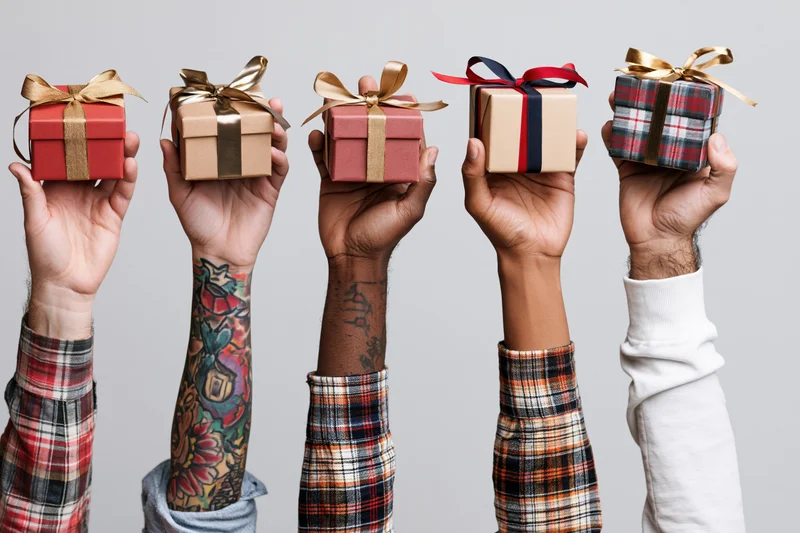 Five diverse hands raised holding wrapped gift boxes against a gray background