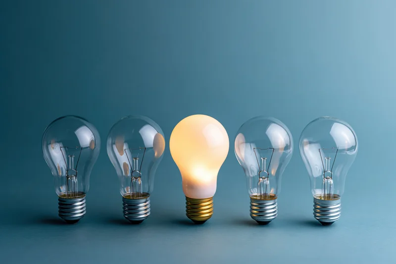 Five incandescent light bulbs in a horizontal row with one glowing against a blue background